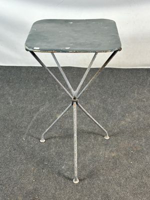 une petite table en métal avec un plateau vert, posée sur un tapis