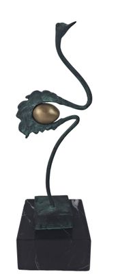 statue of a bird with a golden egg on a black base