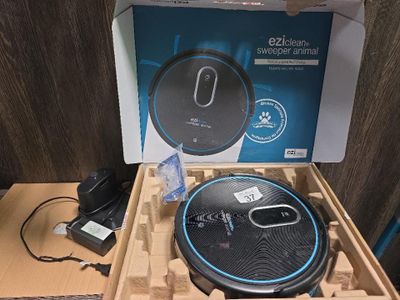 emballage d'un aspirateur robot noir et bleu dans une boîte en carton