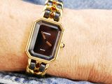 a woman wearing a gold and black watch on her wrist