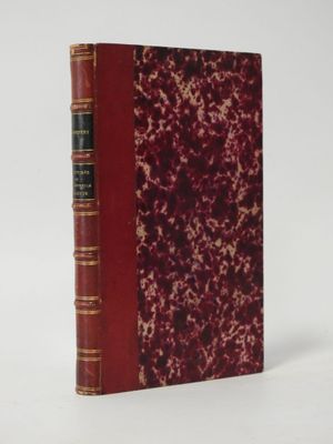 an old book with a red cover sitting on top of a white surface