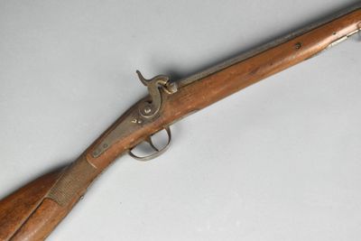 un vieux pistolet avec une poignée en bois sur une surface blanche