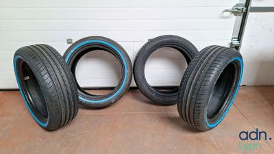 Trois pneus sont alignés sur le sol devant la porte d'un garage.