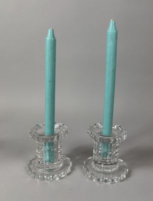 pair of glass candlesticks with turquoise colored candles sitting on top of each other