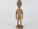 an old wooden figurine of a man standing on a white surface