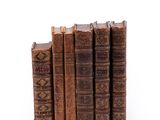 several old books stacked on top of each other on a white surface