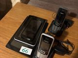 trois téléphones portables posés sur une table à côté d'un chargeur