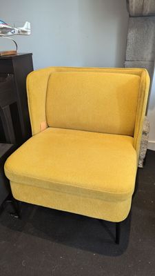 une chaise jaune aux pieds noirs devant une cheminée, avec un feu de cheminée en arrière-plan