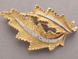 an image of a gold leaf brooch with diamonds on it