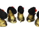 four gold shoes with black and red furs are lined up on a white surface