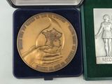a gold medal in a case with a picture of a woman on it