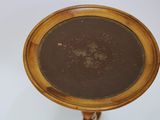 an antique wooden table with a round glass top on a stand