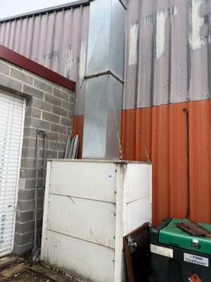 un réfrigérateur blanc posé à l'extérieur d'un immeuble, à côté d'une poubelle verte