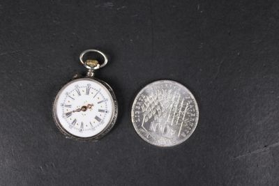 une vieille montre de poche posée à côté d'une pièce de 25 cents