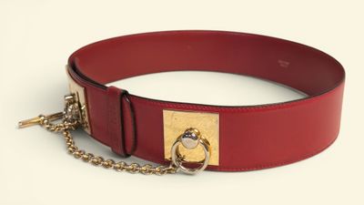 a red belt with a gold buckle and a chain