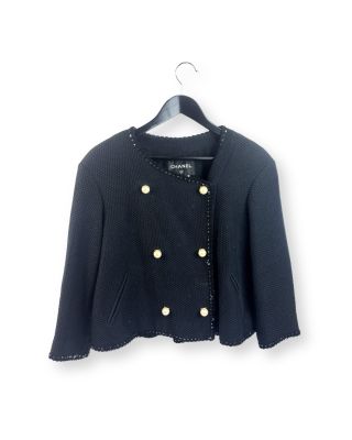 une veste noire à boutons dorés suspendue à un cintre