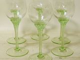 four green wine glasses sitting on top of a white table