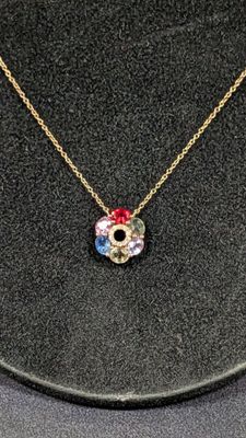 un collier en or orné d'une fleur rouge, blanche et bleue