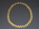 a gold necklace with leaves on a grey background