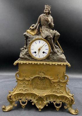 a gold clock with a man sitting on top of it