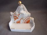 a figurine of a woman sitting on a bed