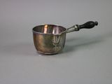 a small silver cup with a black handle on a table