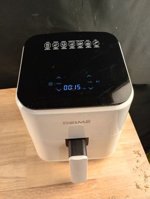 a white and black air fryer on a wooden table