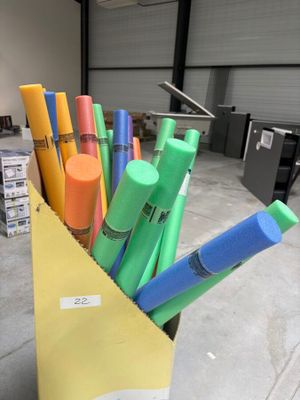 Des stylos aux couleurs vives se trouvent dans un sac en papier, dans un entrepôt.