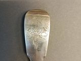 silver spoon with a design on it sitting on a table