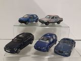 five toy cars on display on a clear shelf