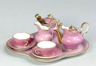 a pink tea set on a tray on a white table