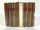 five books are lined up in a row on a white surface