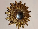 a gold sunburst on the wall above a mirror