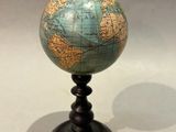 un petit globe bleu et vert posé sur un socle noir
