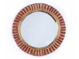 une image représentant un miroir rond orné de rayures rouges et dorées