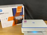 the hp envy printer is sitting on the table next to the box
