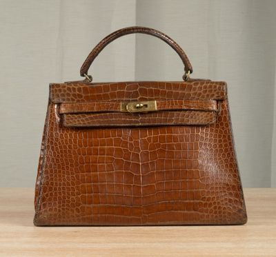 an image of a brown leather handbag sitting on top of a wooden table