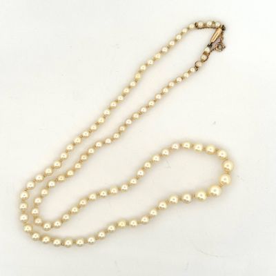 a close up of a necklace with pearls on a white surface