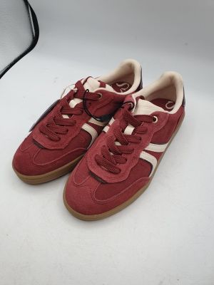 une paire de baskets rouges et blanches posées sur une surface blanche