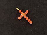 an image of a cross made out of orange beads on a black surface