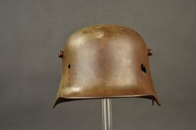 an old helmet on a metal stand against a gray background