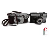two cameras sitting next to each other on a white surface