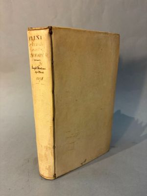 un vieux livre posé sur une table à côté d'un mur blanc