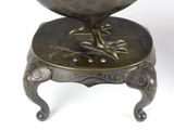 a bronze bird sitting on top of a small stool