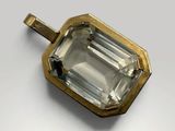 a close up of a green tourmaline pendant on a white surface