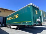 une semi-remorque verte garée devant un immeuble