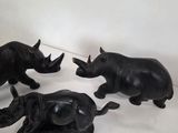 three figurines of rhinos on a white surface