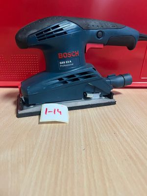 un gros plan d'une ponceuse orbitale Bosch posée sur une table en bois