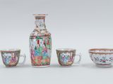 three cups and a vase sitting next to each other