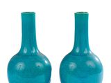 une paire de vases en verre bleu posés sur une surface blanche